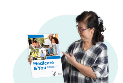 Woman holding the Medicare & You handbook in one hand and pointing at it with the other.