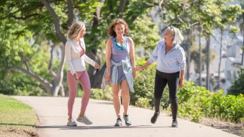 Three women chatting while on a walk in a park