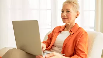 Woman in orange shirt using laptop computer