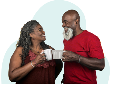 early 60's African American couple wearing red, smiling and facing each other as they clink mugs