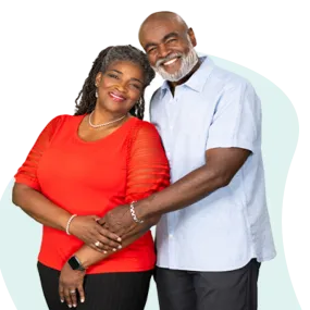 African American couple with arms around each other. She's wearing a red shirt, he's wearing a light blue shirt.