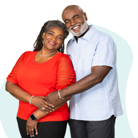 African American couple with arms around each other. She's wearing a red shirt, he's wearing a light blue shirt.
